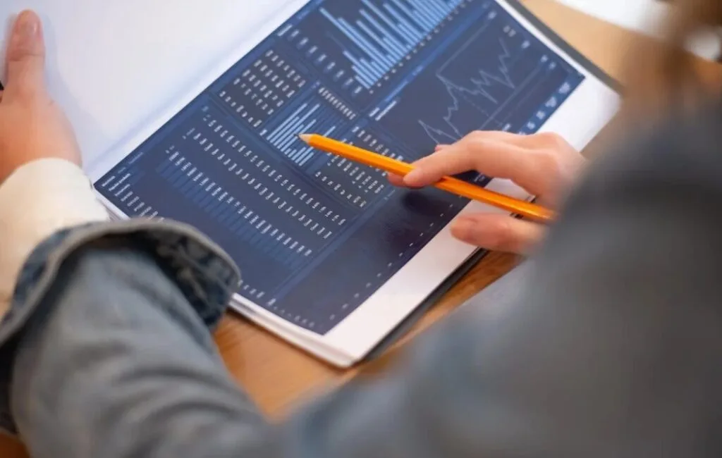 A pencil hovering on a paper with statistical data and a graph.